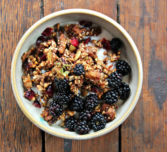 Top-down view of a bowl of granola topped with blackberries.
