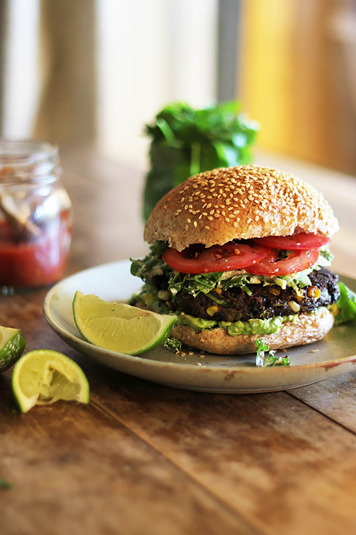 A black bean burger topped with cabbage, avocado, and tomato on a plate.