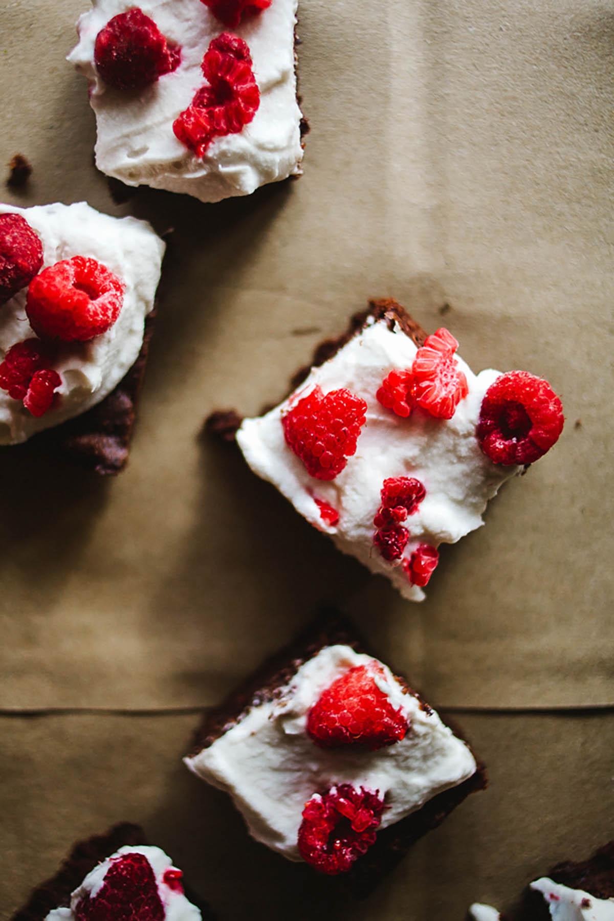 Small brownies topped with cream and raspberries.
