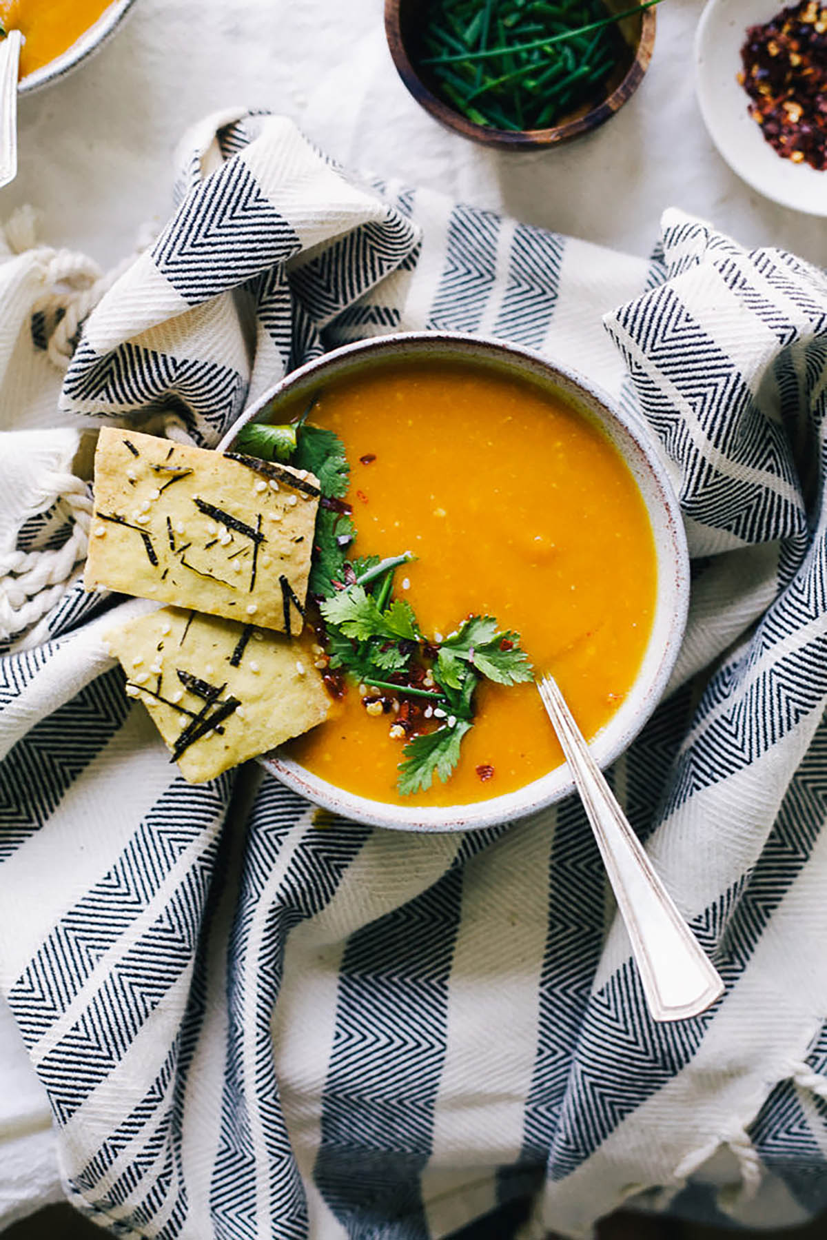 Carrot soup with seaweed crackers on the bowl.