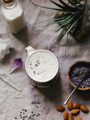 Frothy milk in a mug with lavender blossoms.