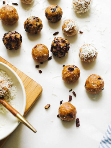 Several energy balls on a white background, coated in cocoa nibs and coconut.