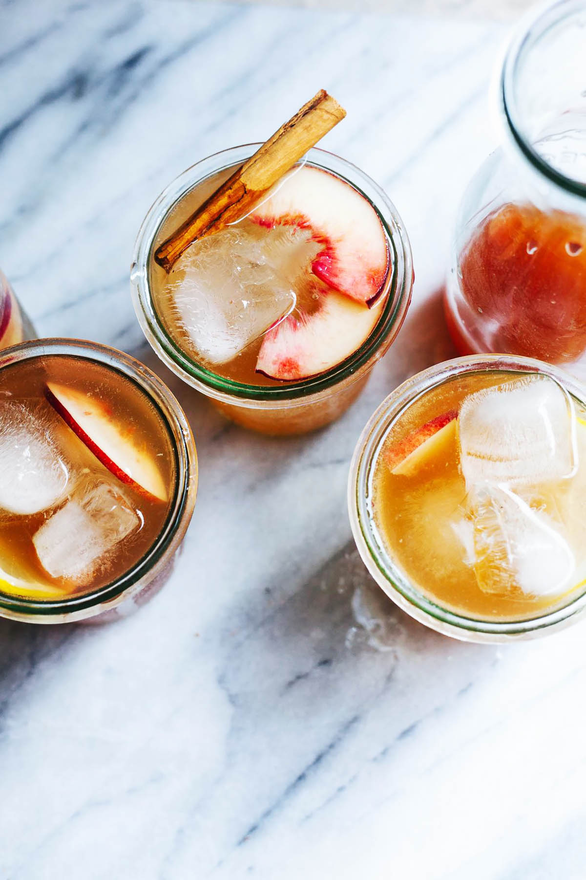 Three glasses of a peach drink topped with ice.