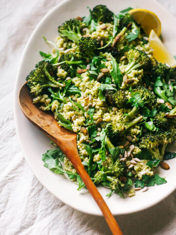 Millet and broccoli salad on a platter with lemon wedges.