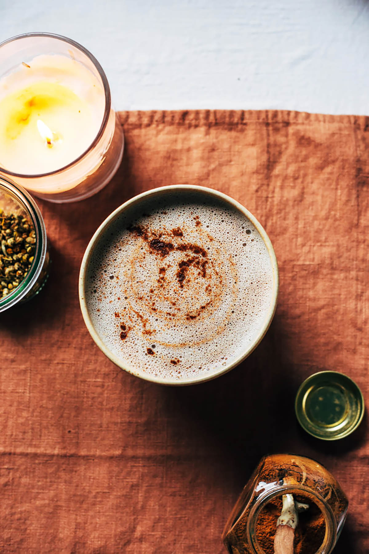 A foamy drink topped with cinnamon with spices around.