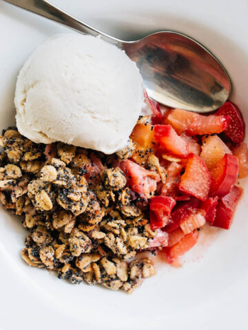 Rhubarb crisp in a bowl with a scoop of ice cream.