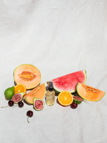 Image of face toner with summer fruit on a white backdrop