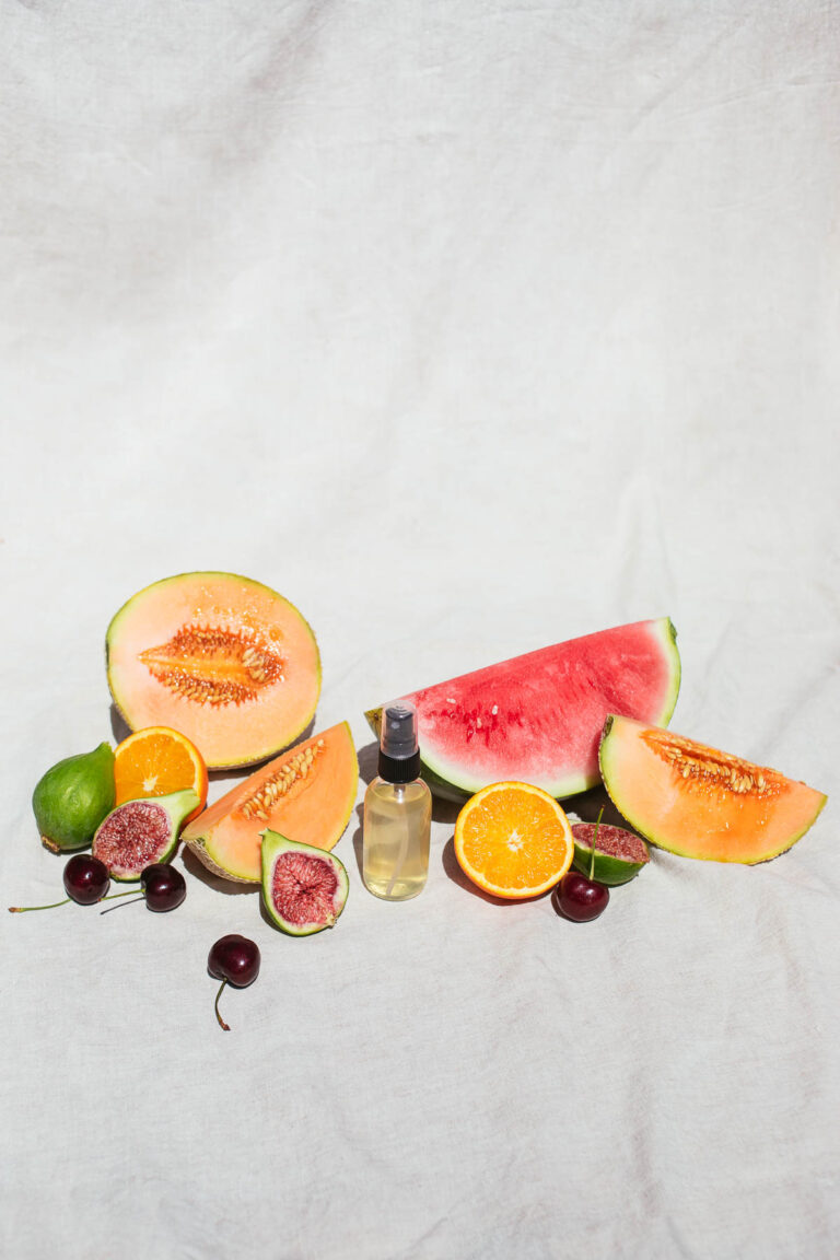 Image of face toner with summer fruit on a white backdrop