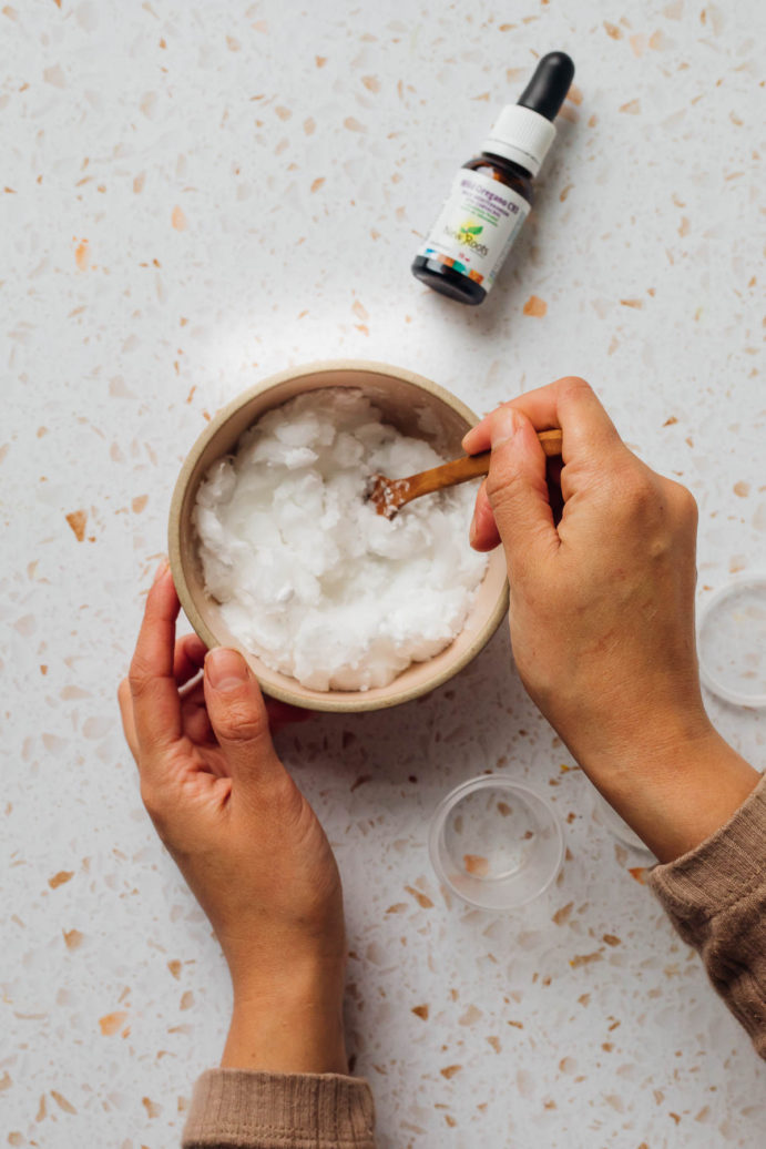 Woman's hands mixing a white paste in a bowl.
