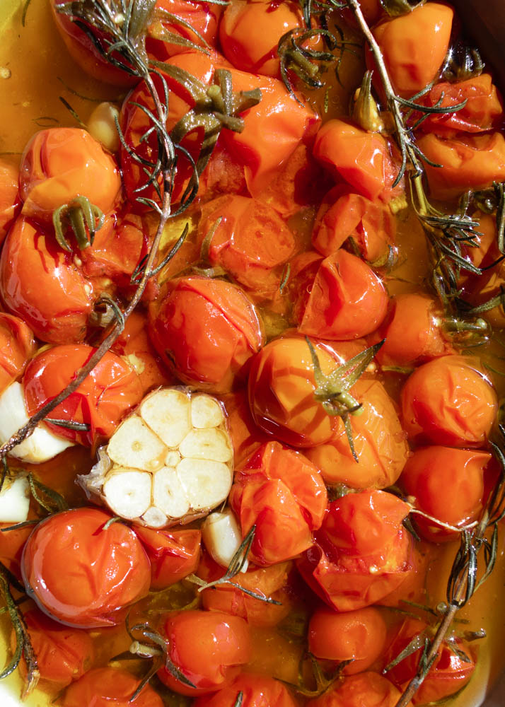 A close up of slow roasted confit tomatoes with garlic and rosemary.