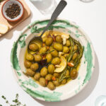 Olives in a serving bowl with oil and flavourings.