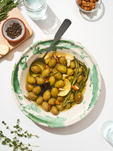 Olives in a serving bowl with oil and flavourings.