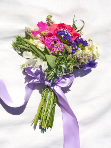 A small flower and herb bouquet tied with purple ribbon.
