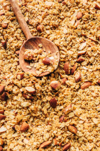 Close up of a pan of granola with a wooden spoon.