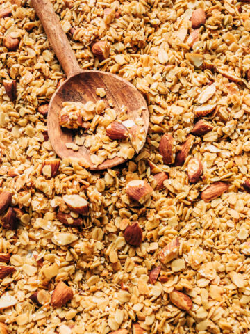 Close up of a pan of granola with a wooden spoon.
