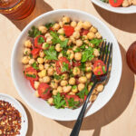 Chickpea salad with herbs and tomatoes in a bowl with a fork.