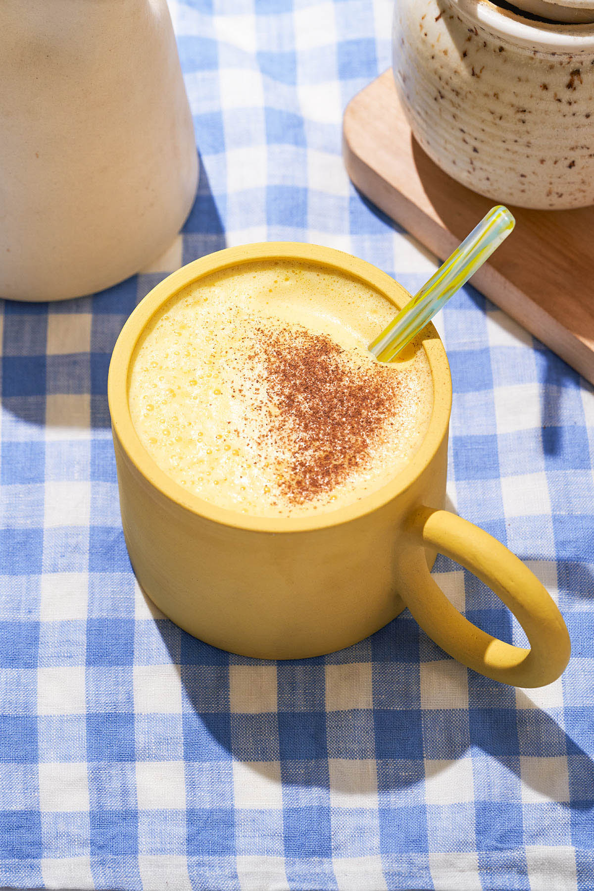 A foamy yellow drink in a yellow mug.