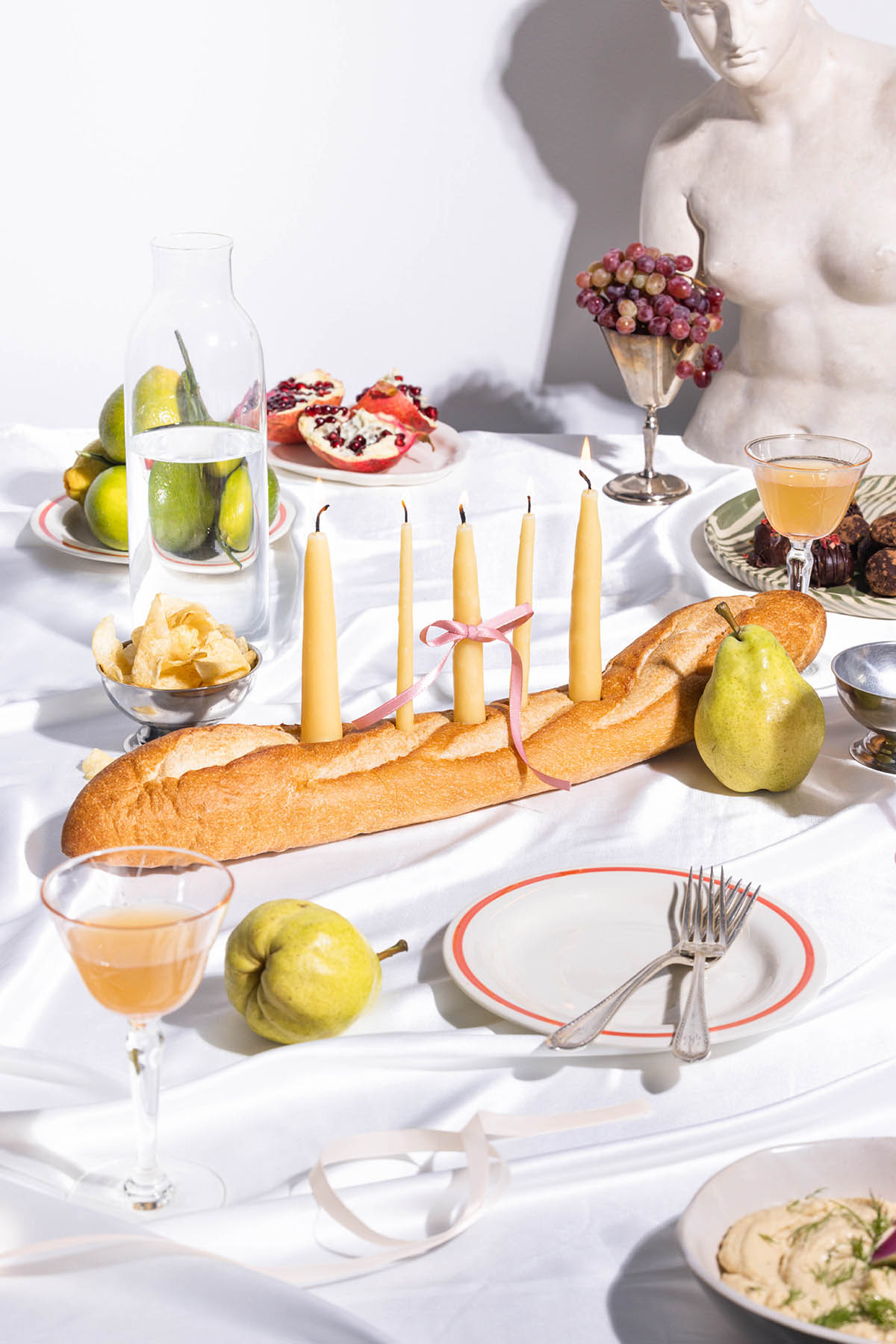 Several beeswax tapers in a baguette on a decorated table.