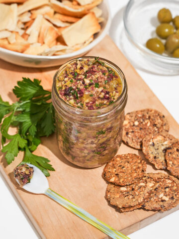 A canning jar filled with tapenade, crackers nearby.