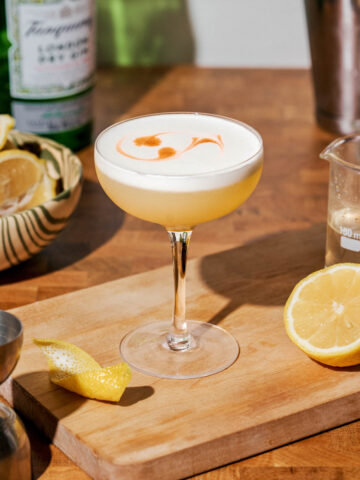 A foamy cocktail in a coupe glass on a kitchen counter.