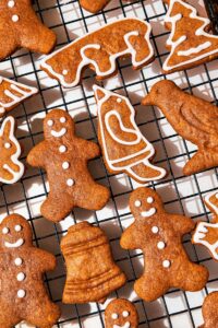 Gingerbread cookie shapes iced with a white icing on a wire rack.