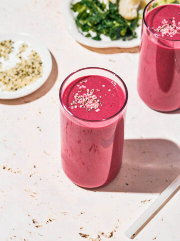 Two glasses filled with a pink smoothie, topped with hemp hearts.