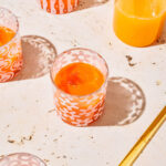Several glasses of orange coloured juice in small cups.