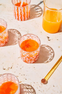 Several glasses of orange coloured juice in small cups.