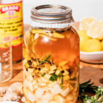 A jar of infused apple cider vinegar on a kitchen counter.