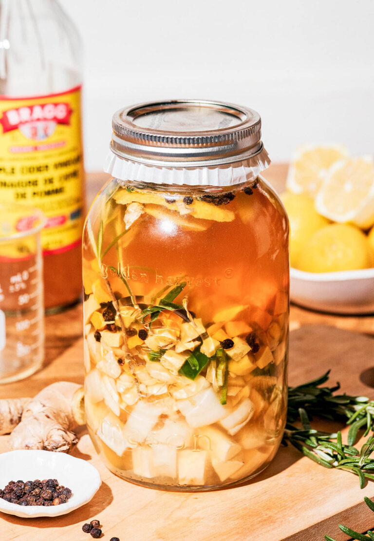 A jar of infused apple cider vinegar on a kitchen counter.