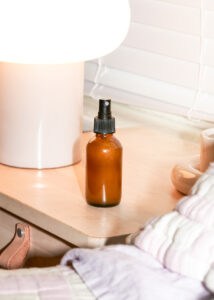 A small brown glass spray bottle on a bedside table.