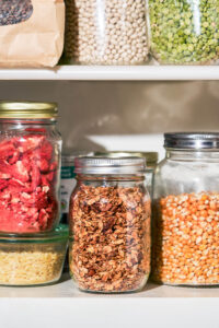 Several jars on shelves, filled with dry foods.
