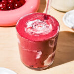 Pink smoothie swirled with white yogurt, cherries in the background.