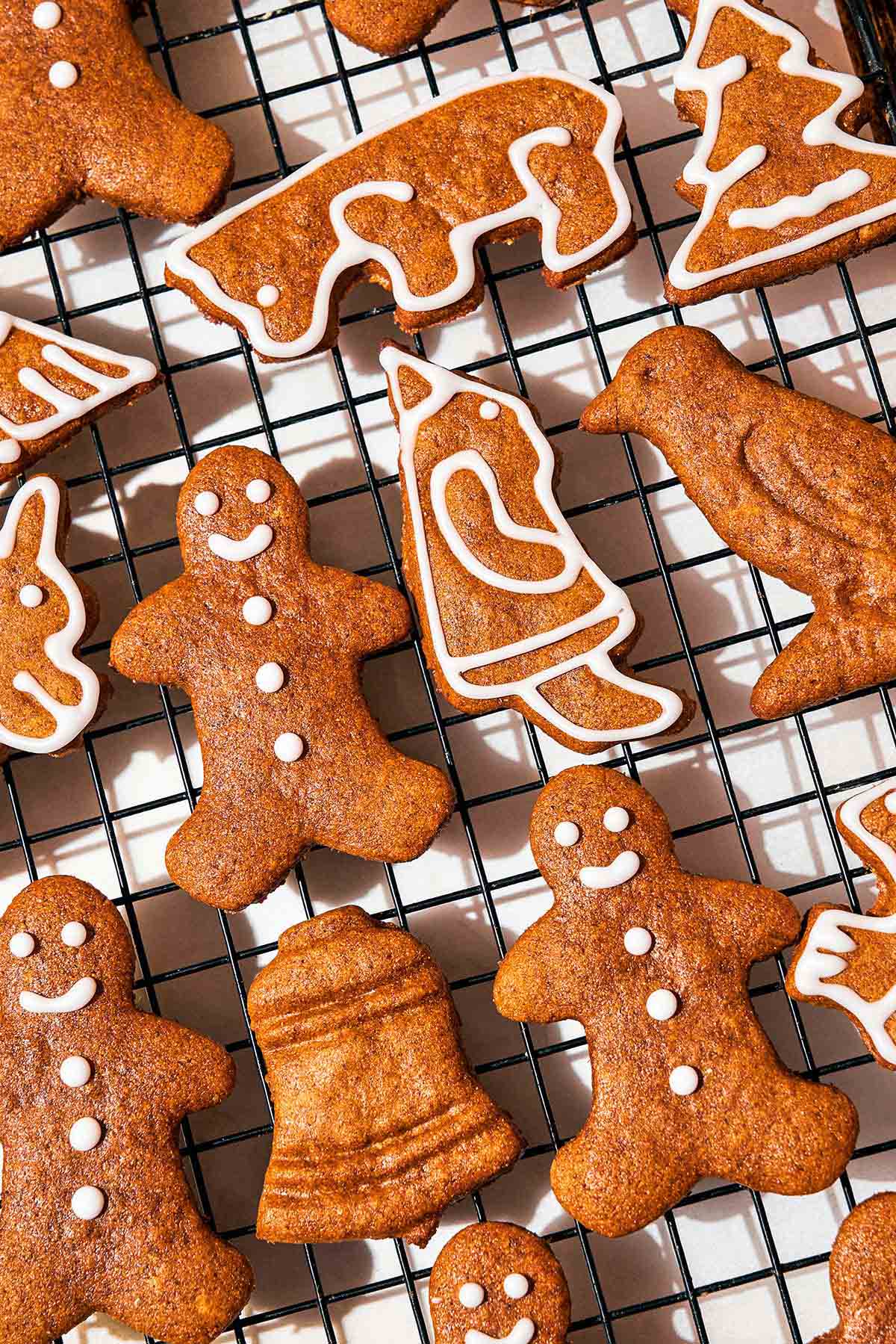 Gingerbread cookie shapes iced with a white icing on a wire rack.